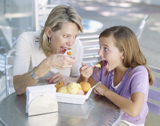 Miami, Florida, USA --- Woman and young girl on outdoor patio eating ice cream --- Image by © Ocean/Corbis